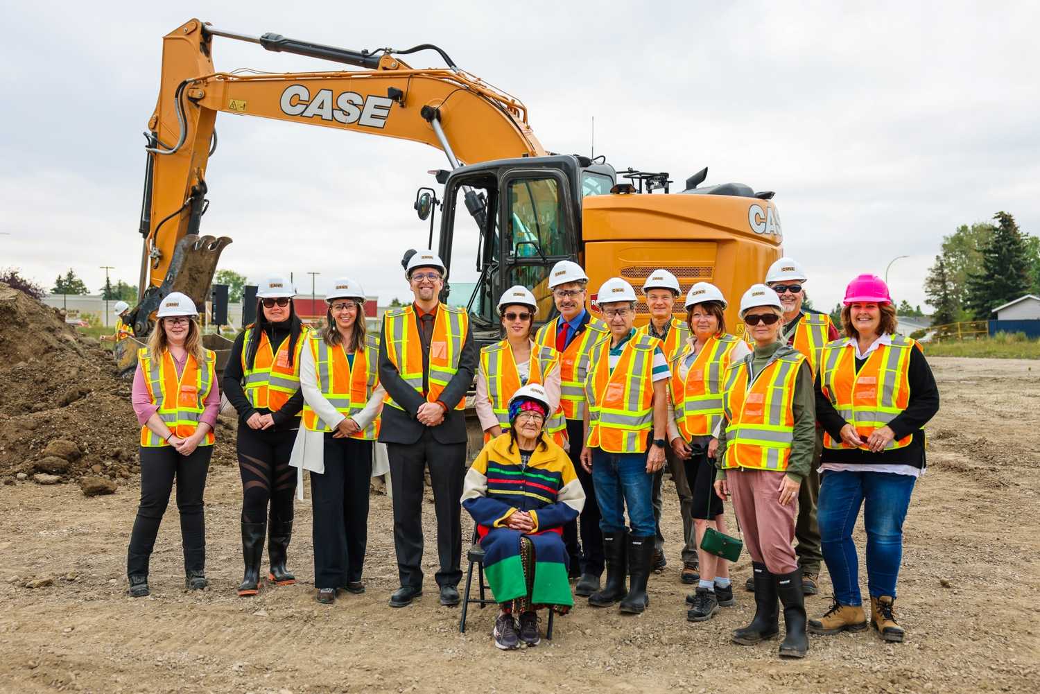 Project team members stand in front of construction equipment on site of new facility